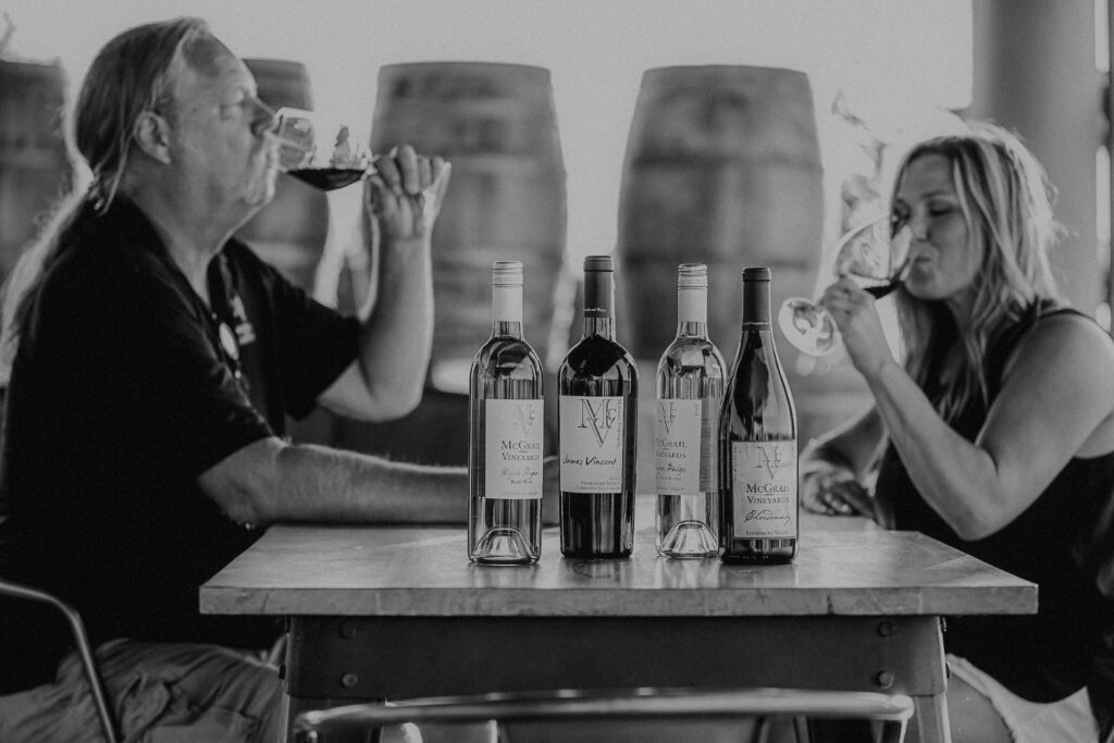 McGrail Vineyards wine bottles displayed during a tasting with guests in the background.