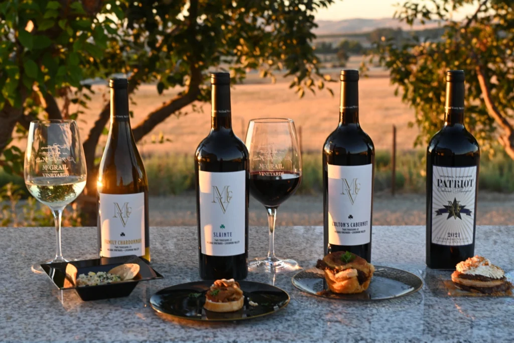 McGrail wine bottles and tasting pairings served outdoors with vineyard views at sunset.