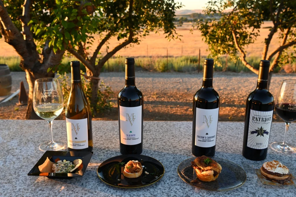McGrail wine bottles and tasting pairings set outdoors with vineyard views at sunset.