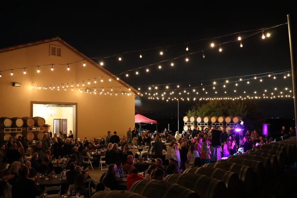 McGrail Vineyards Cattle Cabernet Country evening with guests, vineyard barrels, lights, and live music.