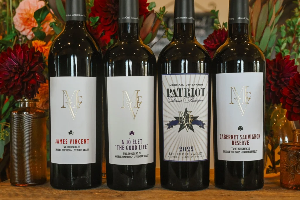 McGrail Vineyard wine bottles with white labels displayed against a colorful floral background.