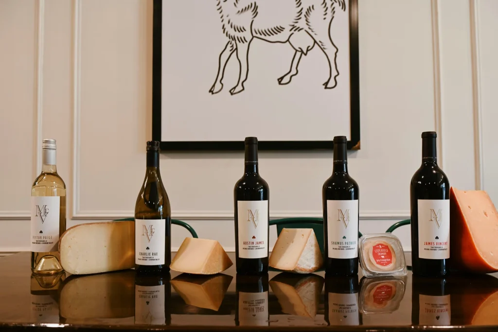 McGrail Vineyard wine bottles displayed with various aged cheeses on a reflective black surface.